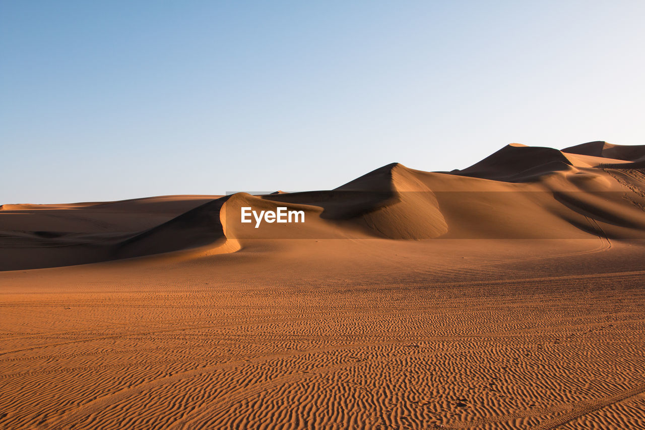 Sand dunes in desert against clear sky