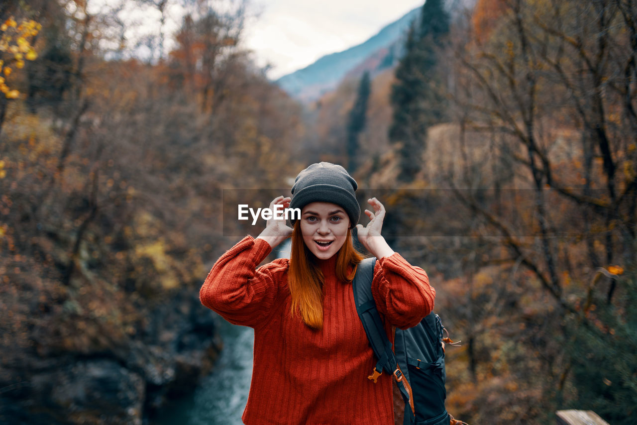 WOMAN WEARING HAT STANDING IN FOREST DURING AUTUMN