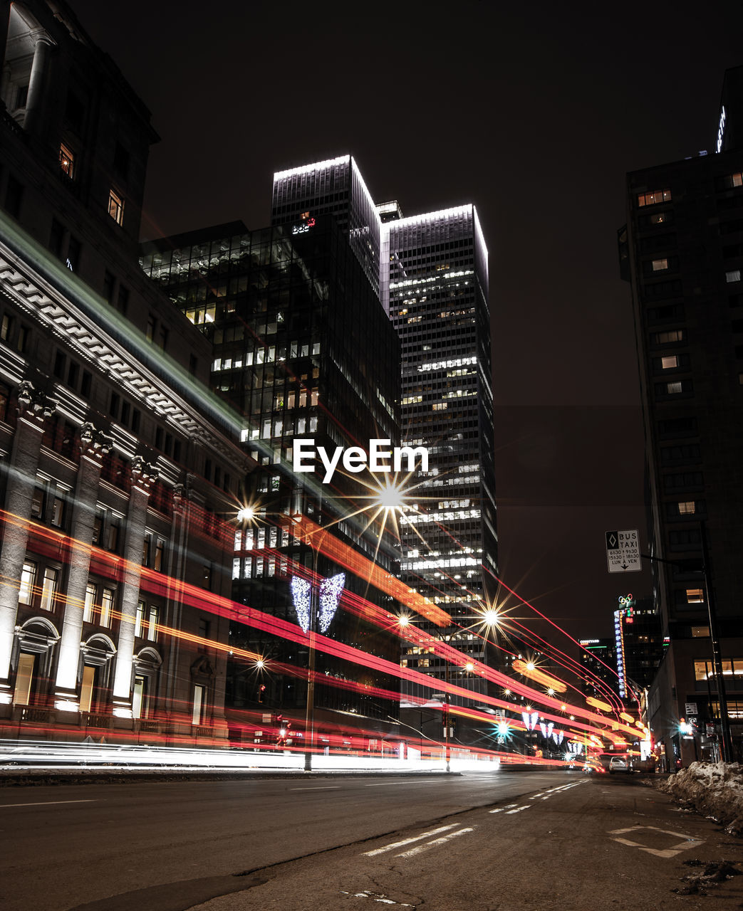 Illuminated city street and buildings against sky at night