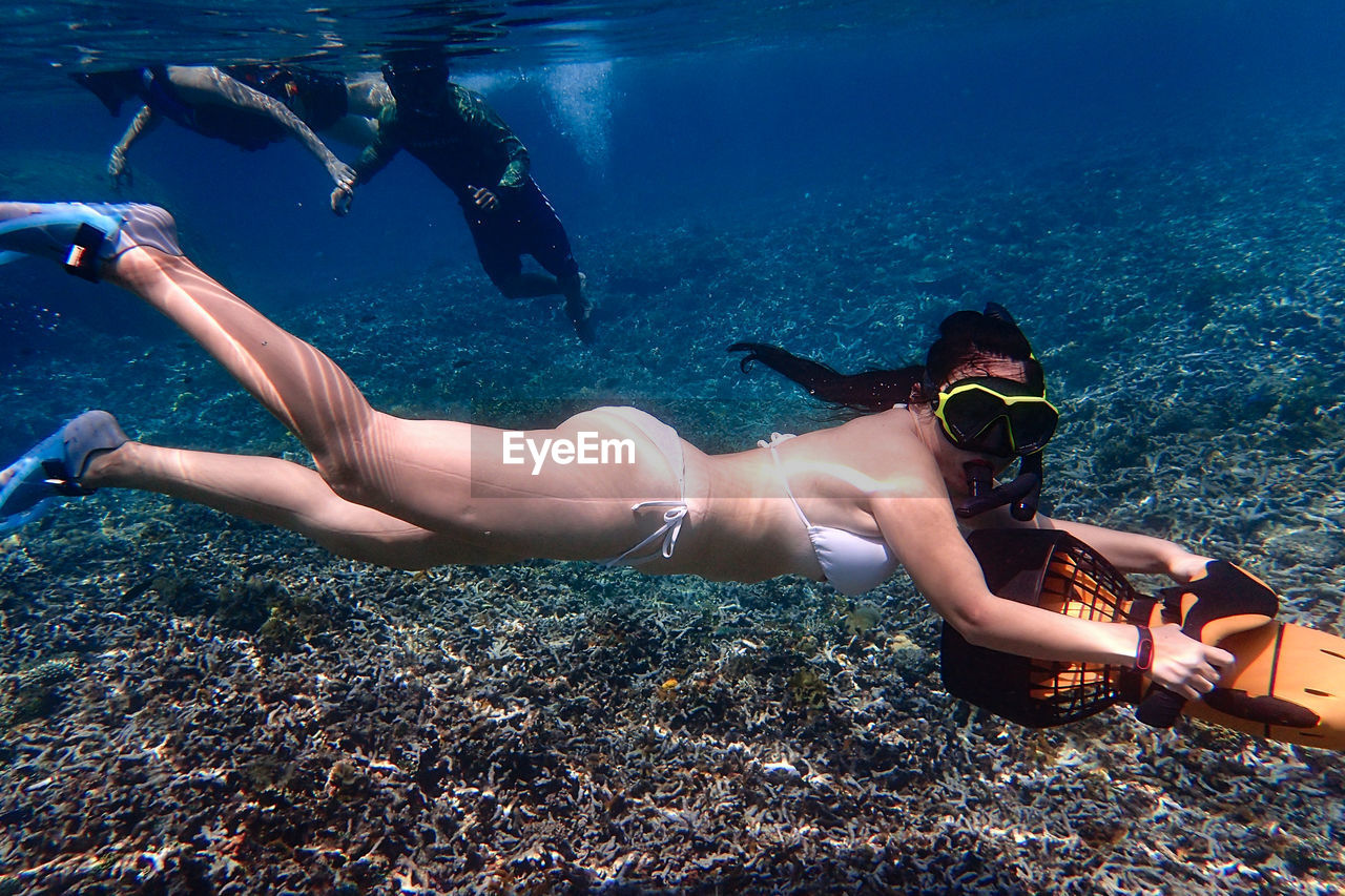 MIDSECTION OF WOMAN SWIMMING IN SEA