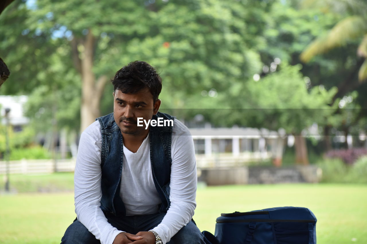 Thoughtful man sitting on bench at park