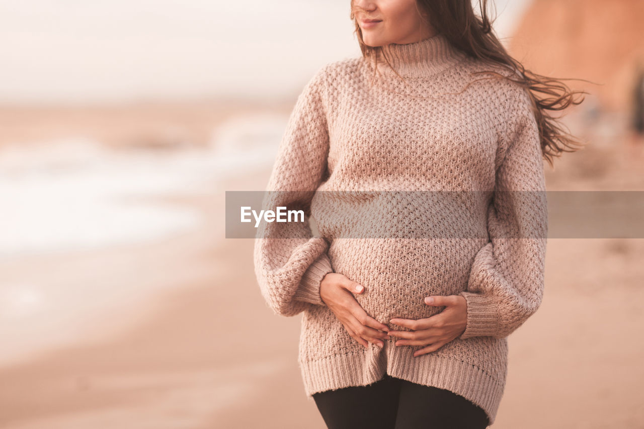 Midsection of woman standing on beach