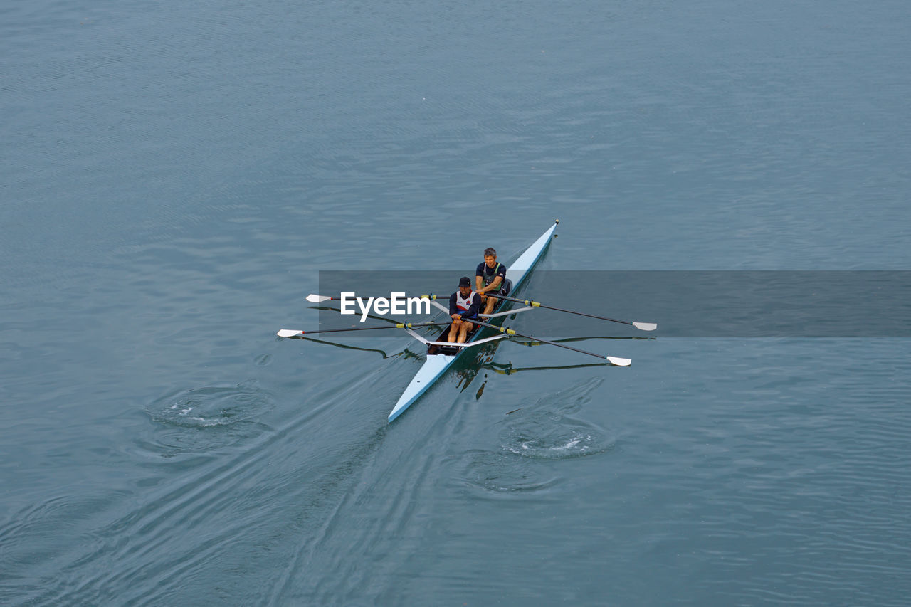 water, nautical vessel, transportation, rowing, sports, oar, nature, high angle view, cooperation, teamwork, mode of transportation, men, adult, sculling, day, competition, boating, lake, motion, sport rowing, water sports, togetherness, outdoors, recreation, copy space, rowboat, young adult, scull, vehicle, group of people, blue, lifestyles, boat, athlete, leisure activity