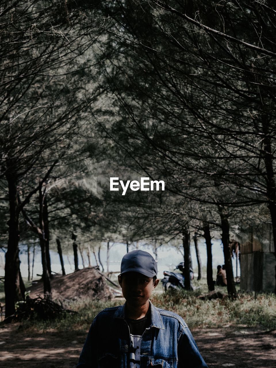 Young man standing against trees