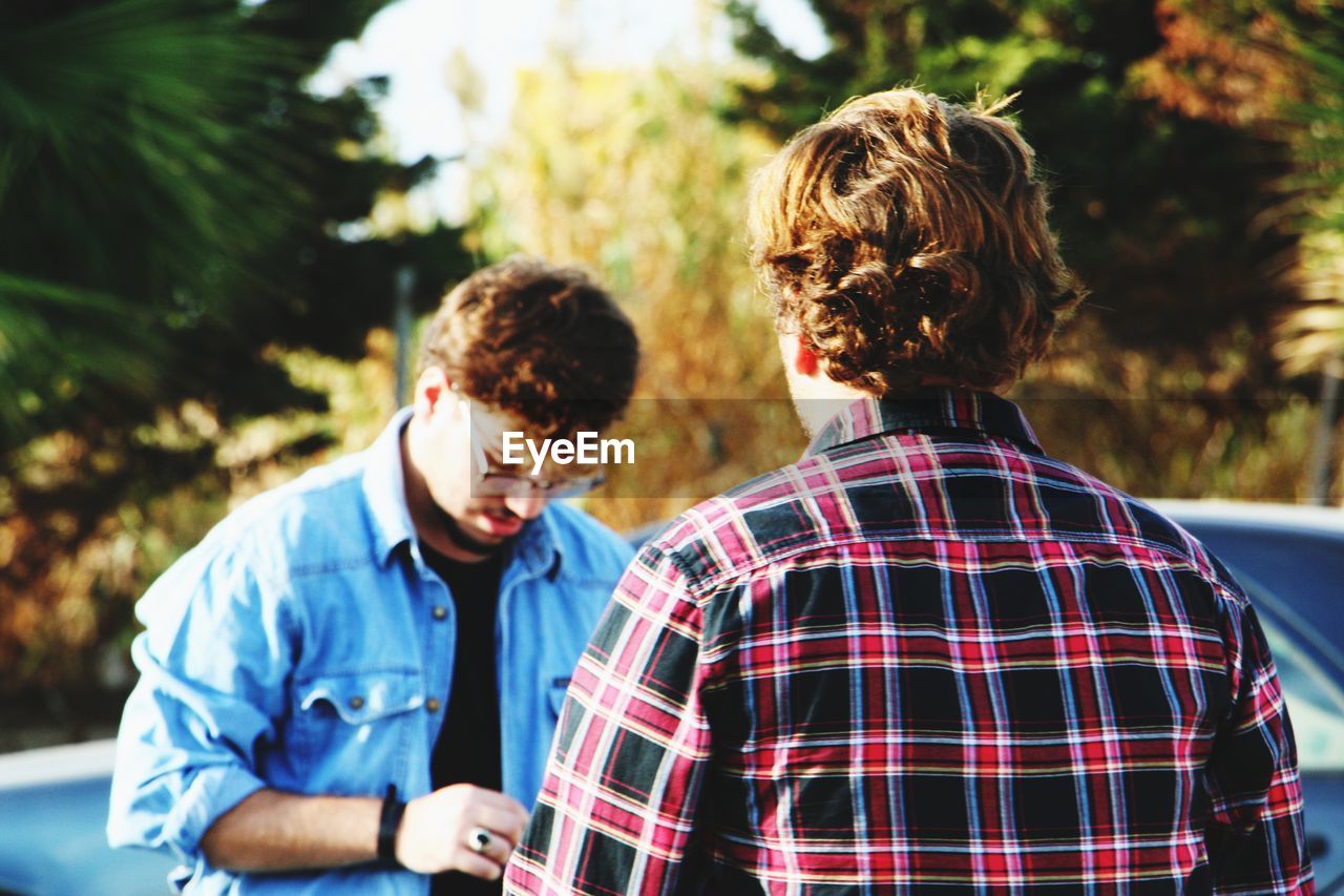 Male friends standing against trees