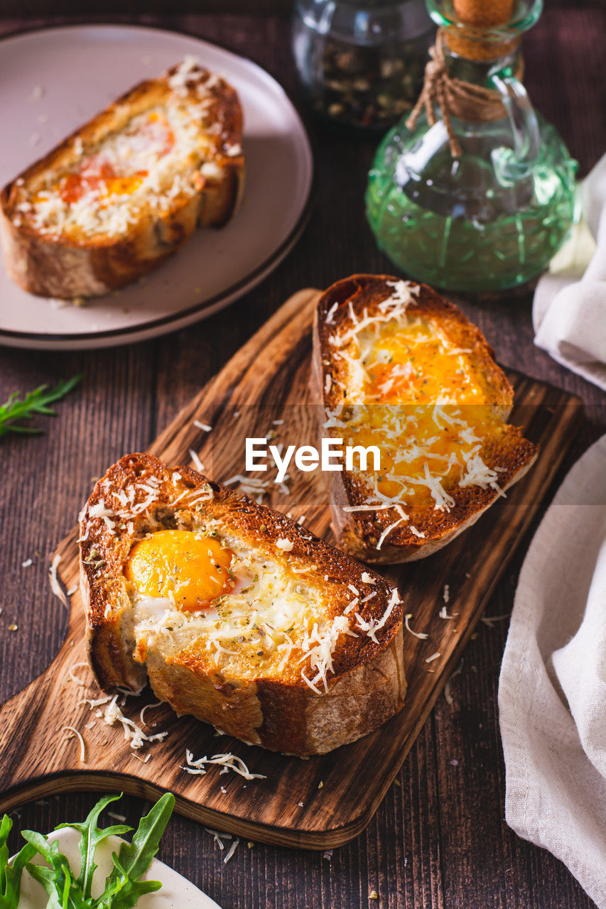 Appetizing brioche baked with egg and cheese on the board vertical view