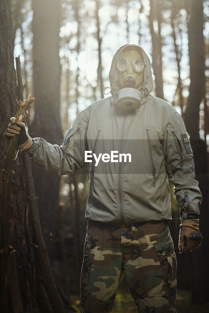 Midsection of man standing by tree in forest