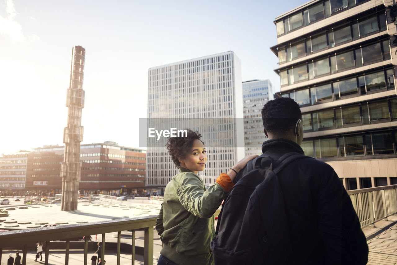 Portrait of teenage girl walking with friend on bridge in city