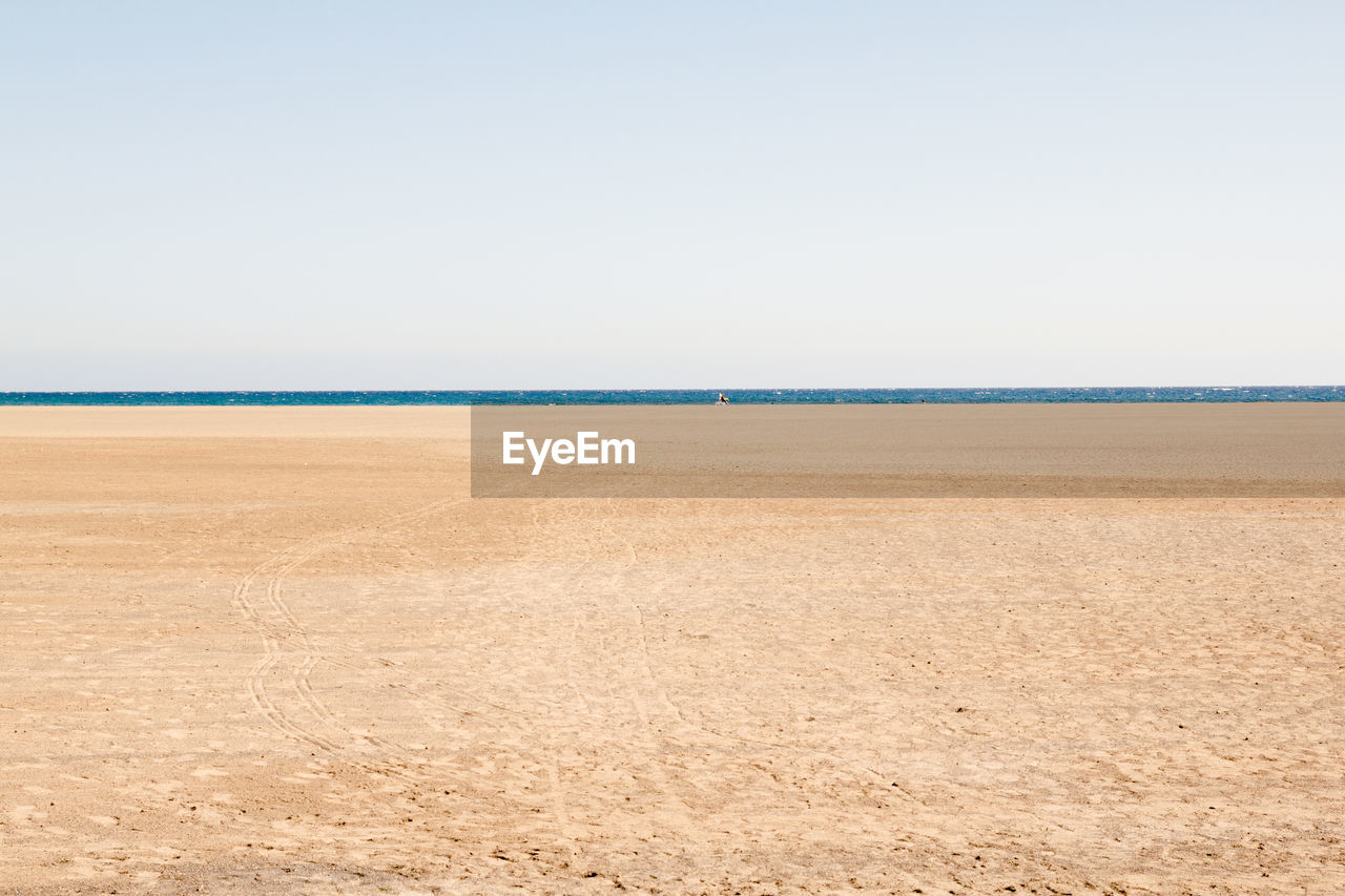 Scenic view of beach against clear sky on sunny day