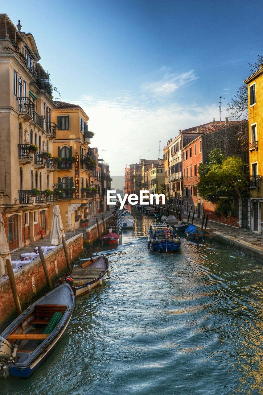 Boats in canal amidst buildings against sky