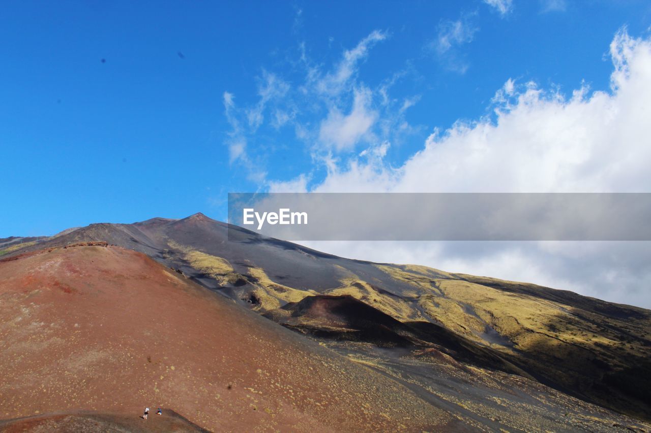 Scenic view of volcanic mountain against blue sky