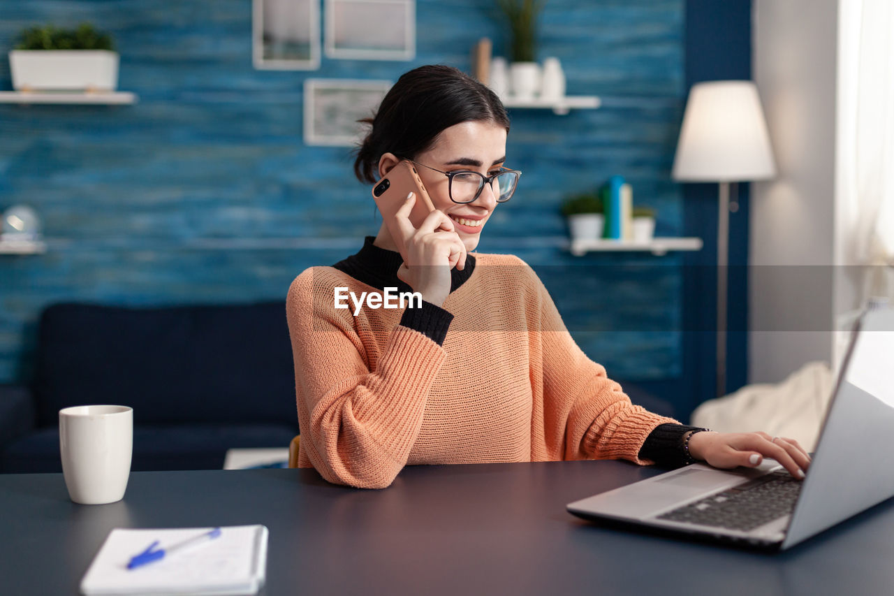 Midsection of woman using mobile phone while sitting on table