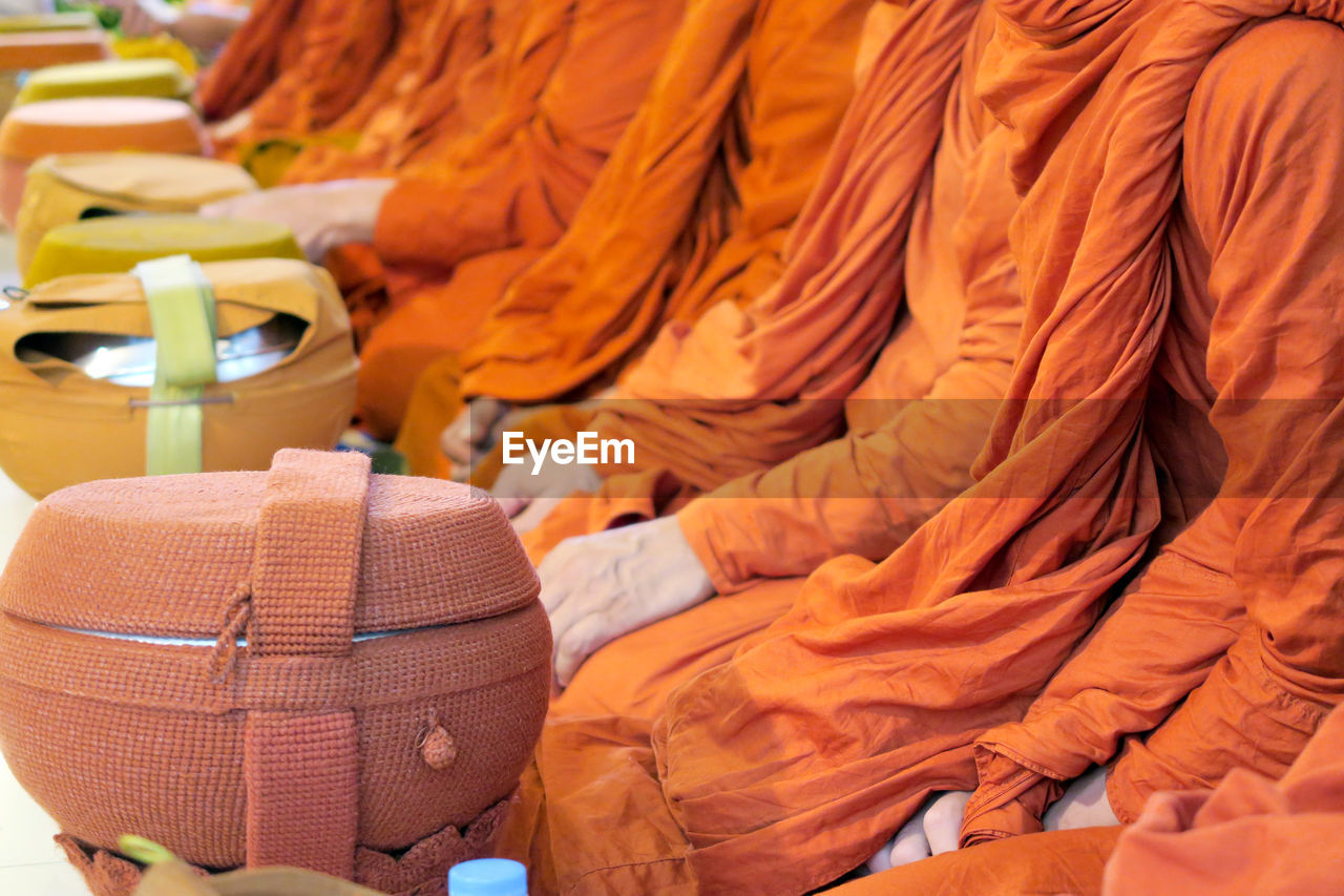 Midsection of monks with container sitting in row