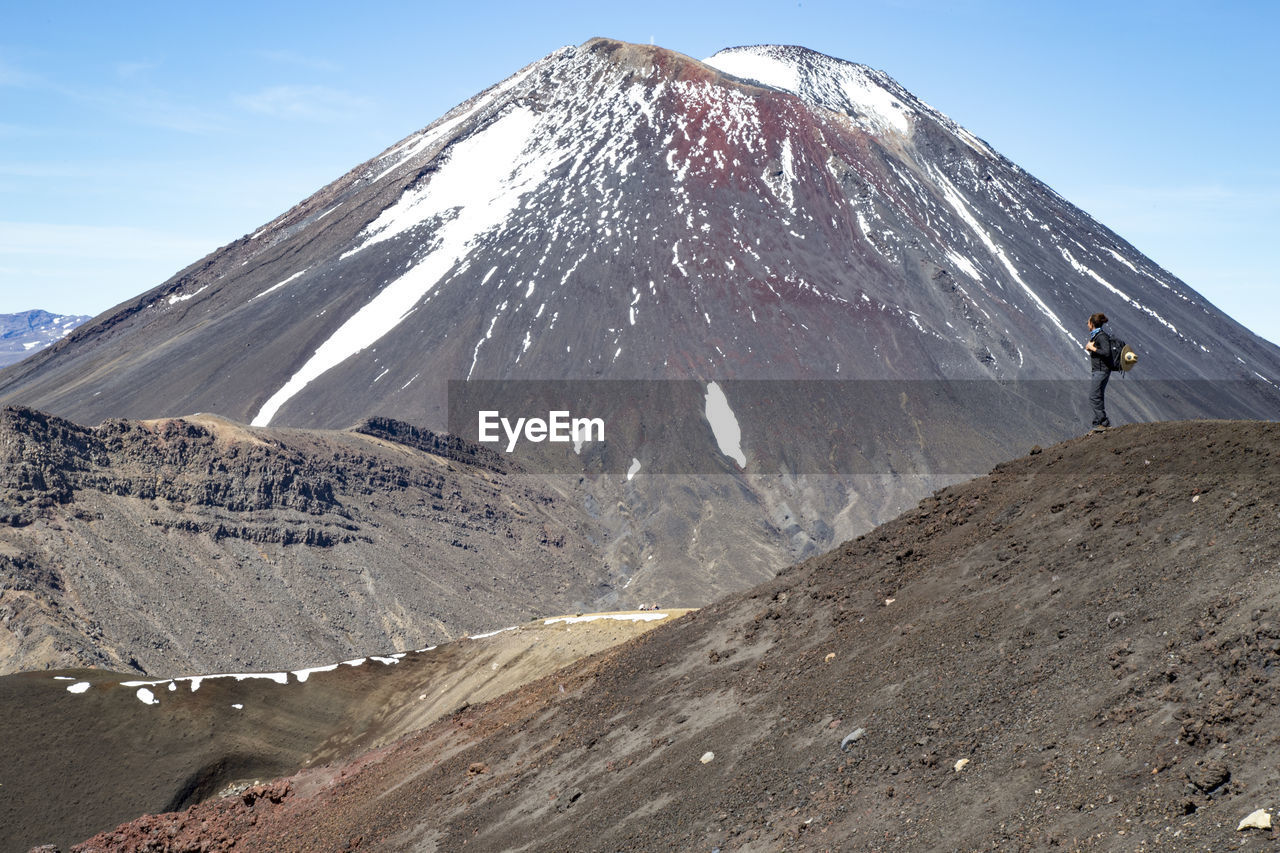 Male hiker with backpack, looking at the view and a snowed volcano