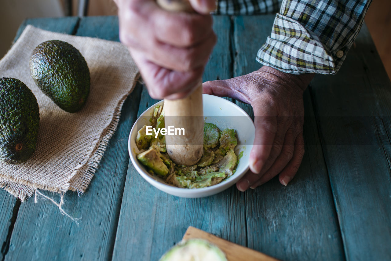 Hands of man mashing avocado for guacamole
