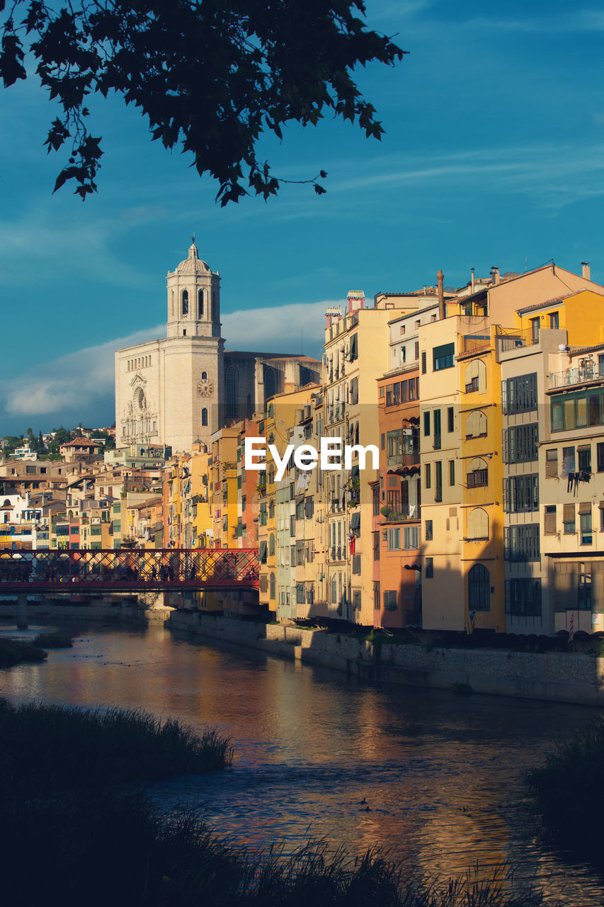 Buildings by river against sky in city