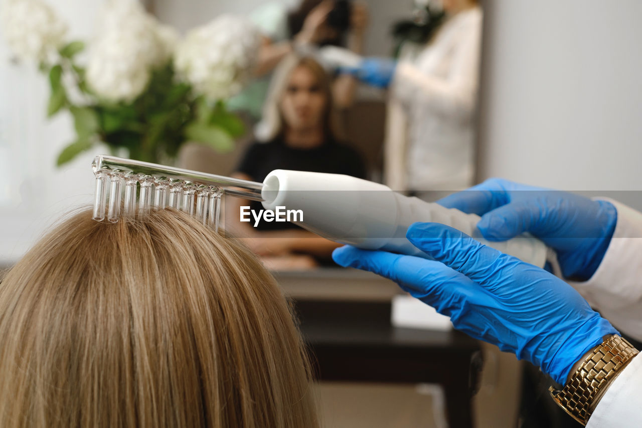 Doctor examines head skin of a young girl with special dermatology equipment system, hair loss and