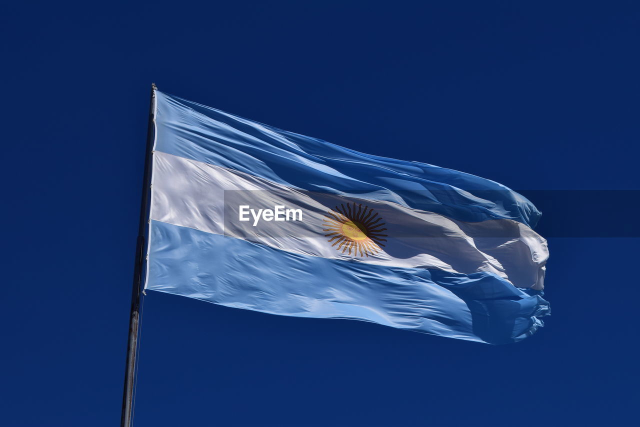 Low angle view of argentinean flag against blue sky