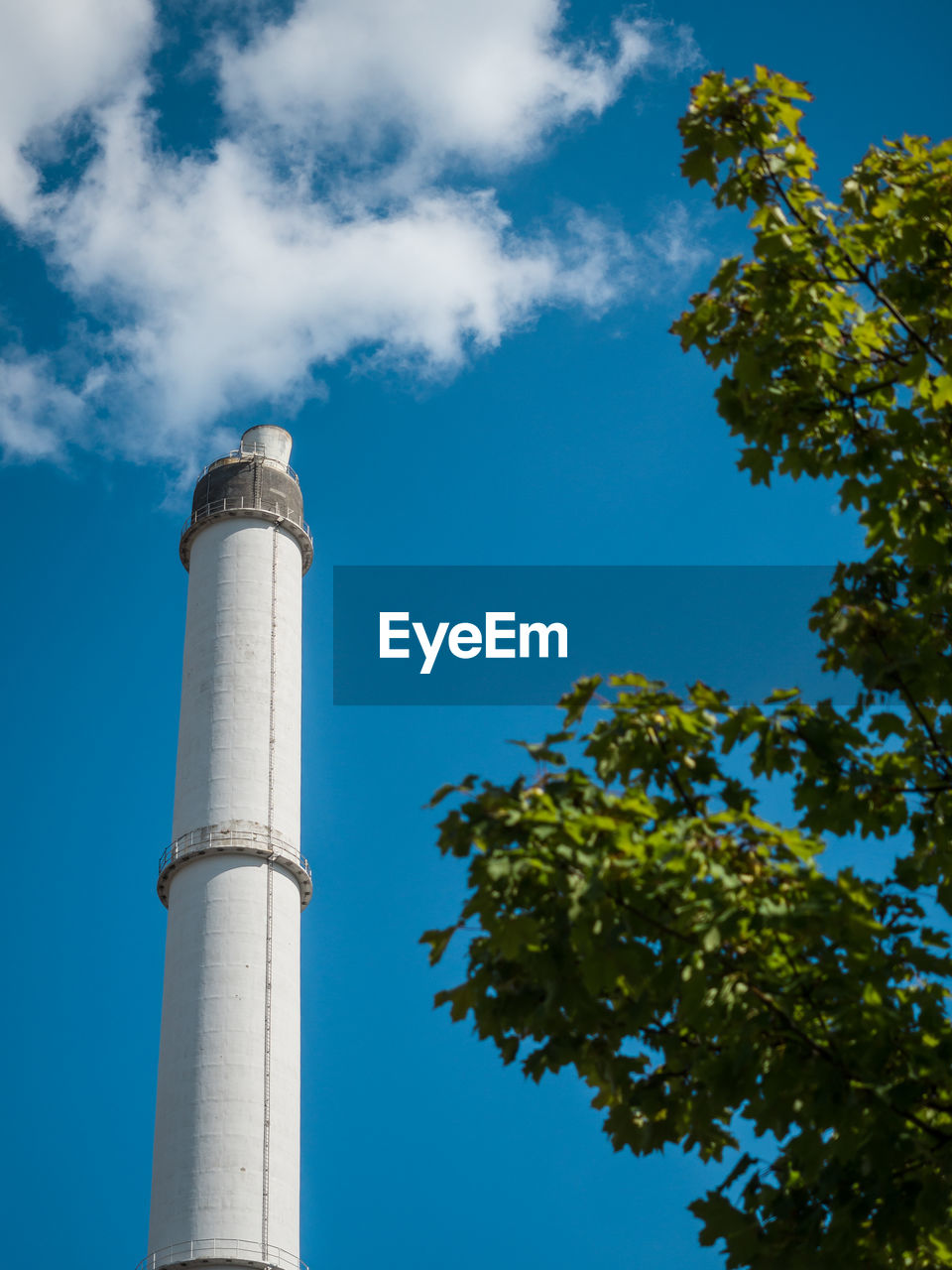 Low angle view of chimney and tree against sky