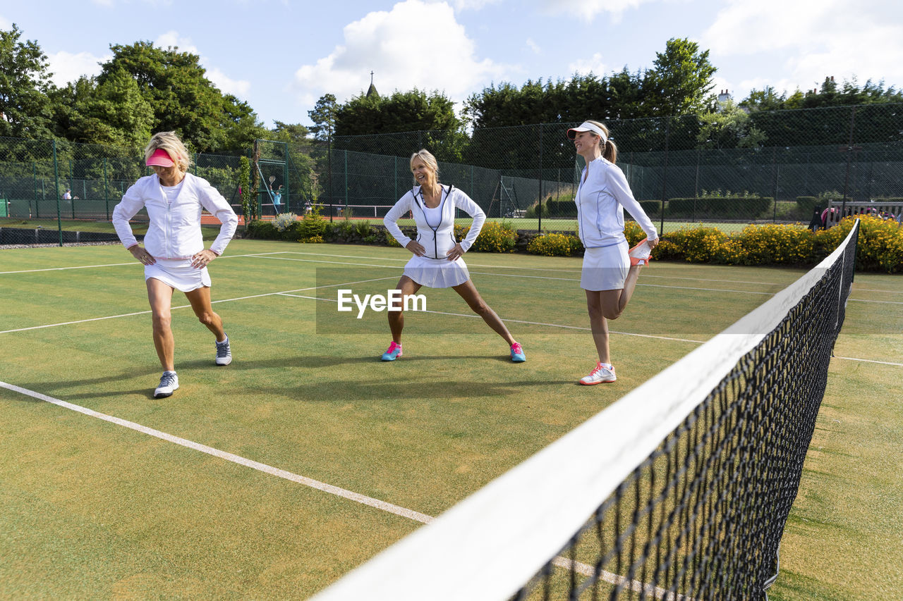 Mature women doing stretching exercises before playing tennis