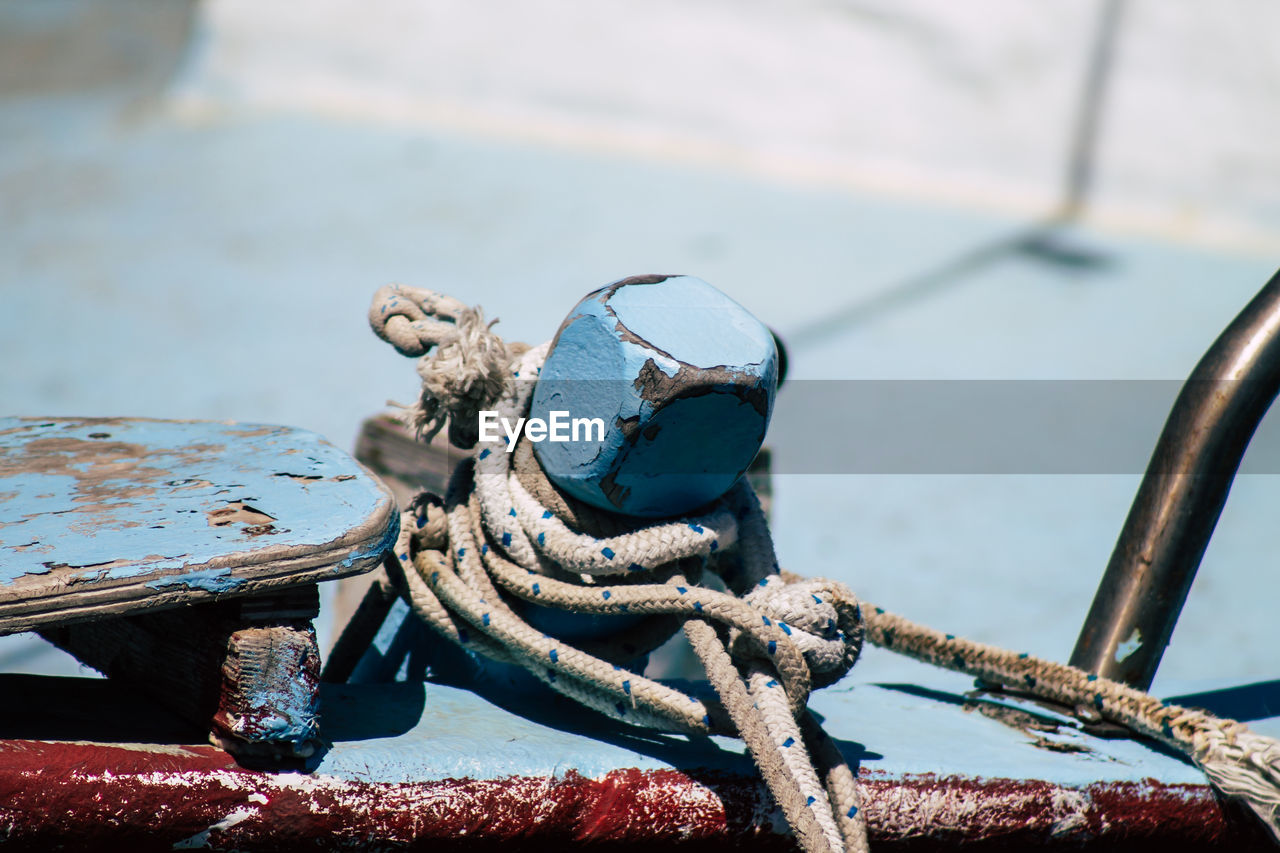 CLOSE-UP OF ROPE TIED UP ON RUSTY METAL