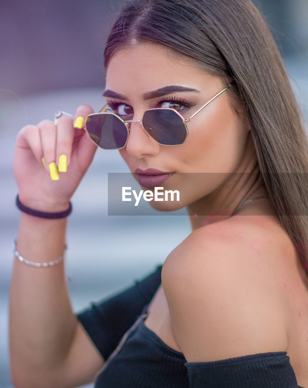 PORTRAIT OF YOUNG WOMAN HOLDING SUNGLASSES OUTDOORS