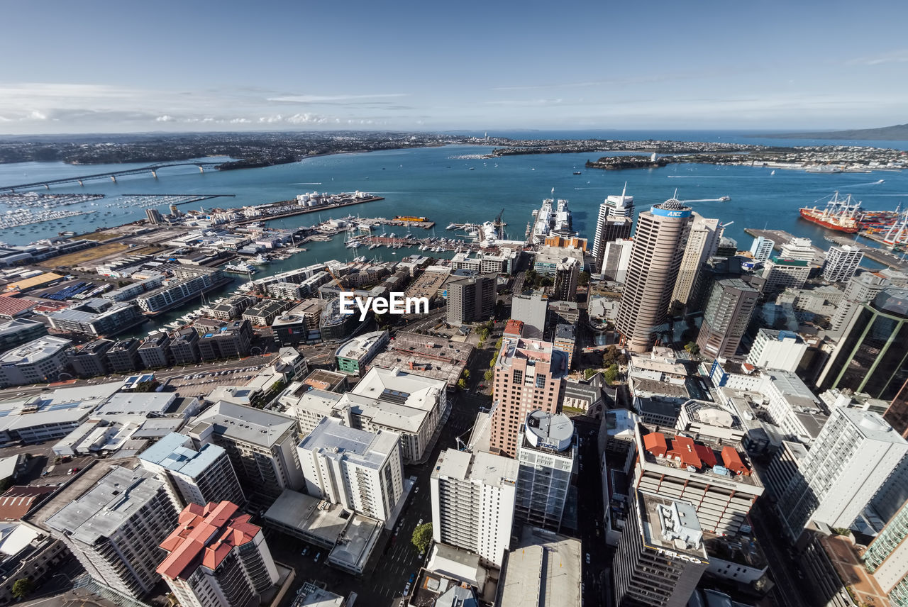 Aerial view of buildings by sea against sky