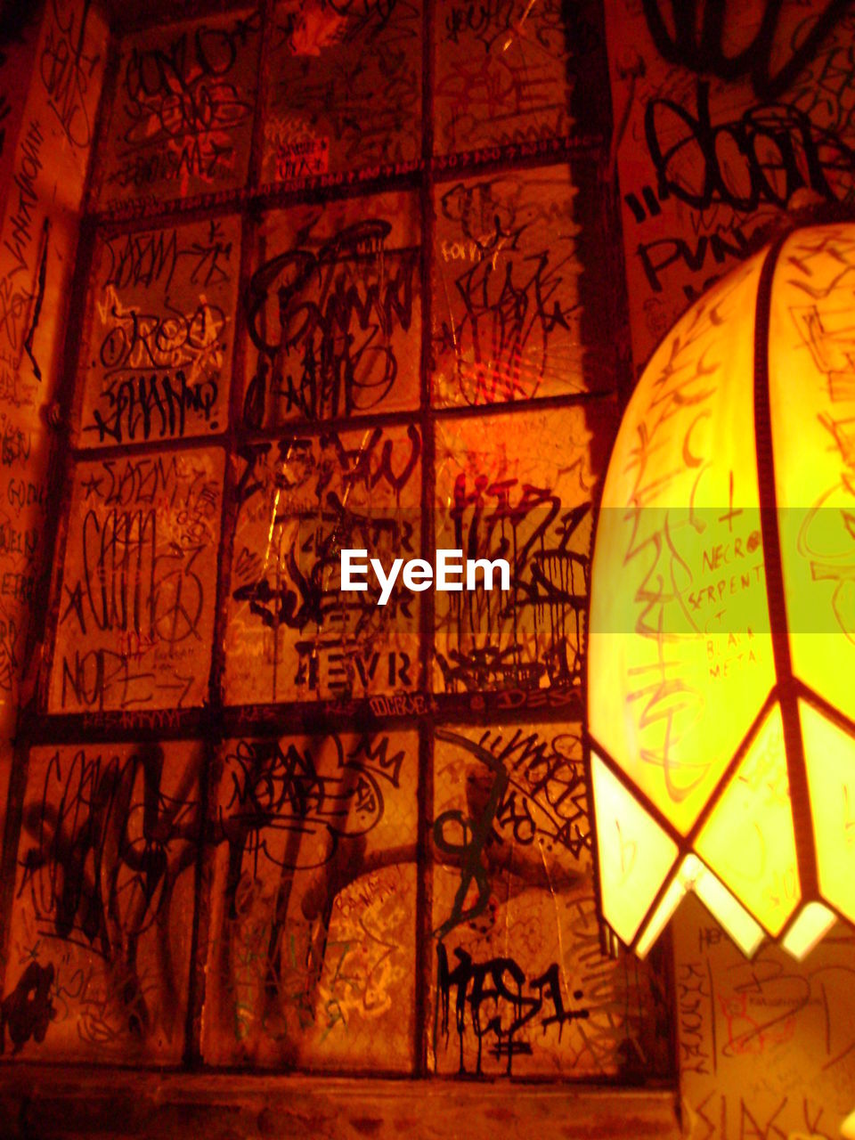 Illuminated lantern against graffiti on wall