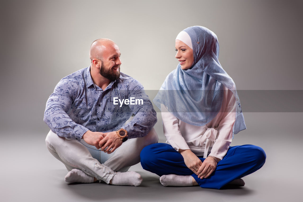 YOUNG COUPLE SITTING ON WALL WITH HANDS