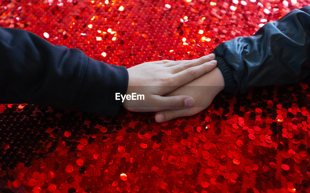 Cropped hands of children on red glitters