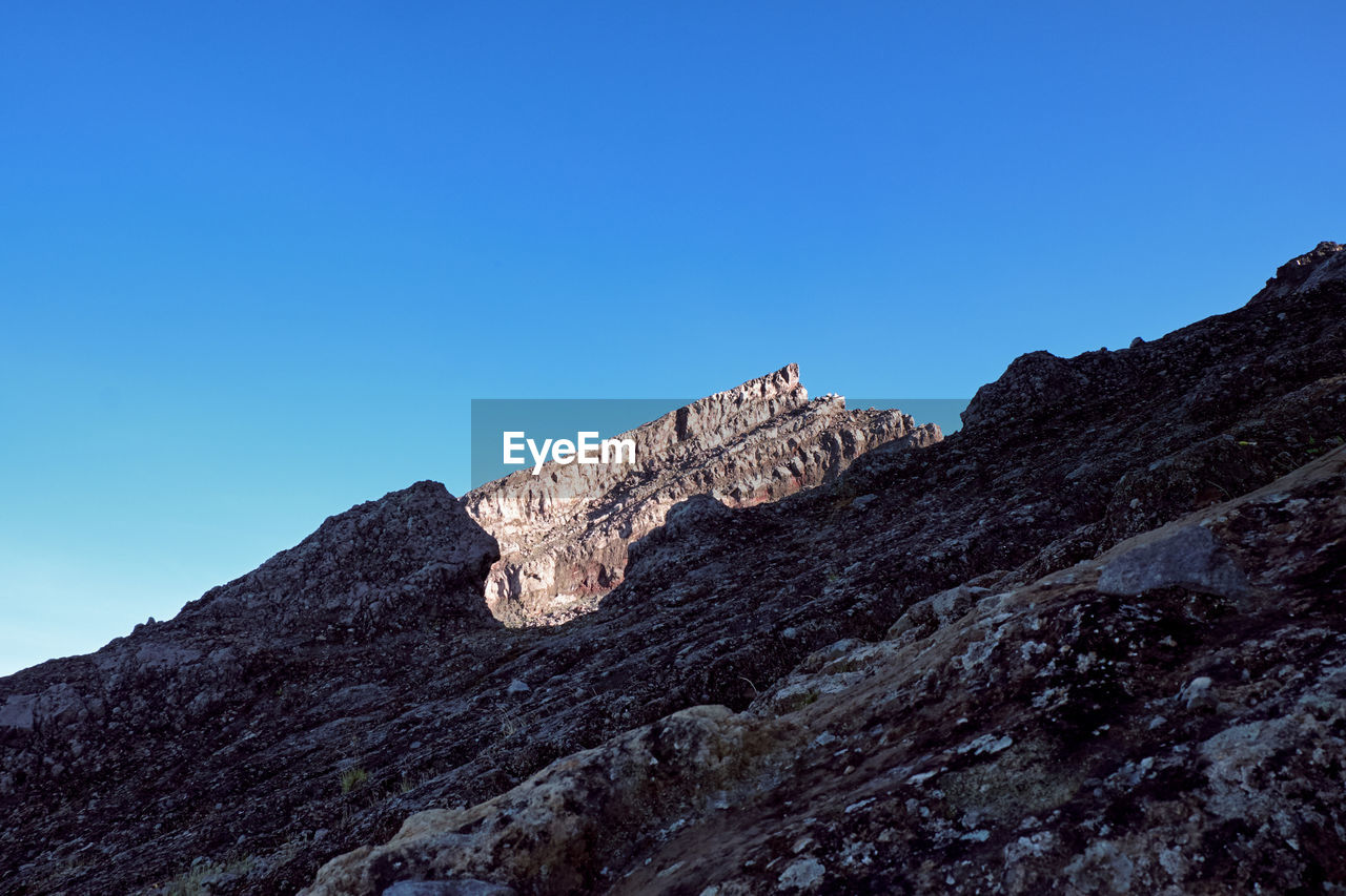 Low angle view of rock formation against clear blue sky