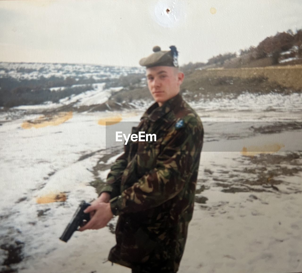 one person, water, sea, clothing, nature, land, adult, beach, portrait, looking at camera, standing, winter, three quarter length, young adult, day, snow, sports, holding, men, gun, person, outdoors, cold temperature, military, waist up, weapon, leisure activity, motion, government