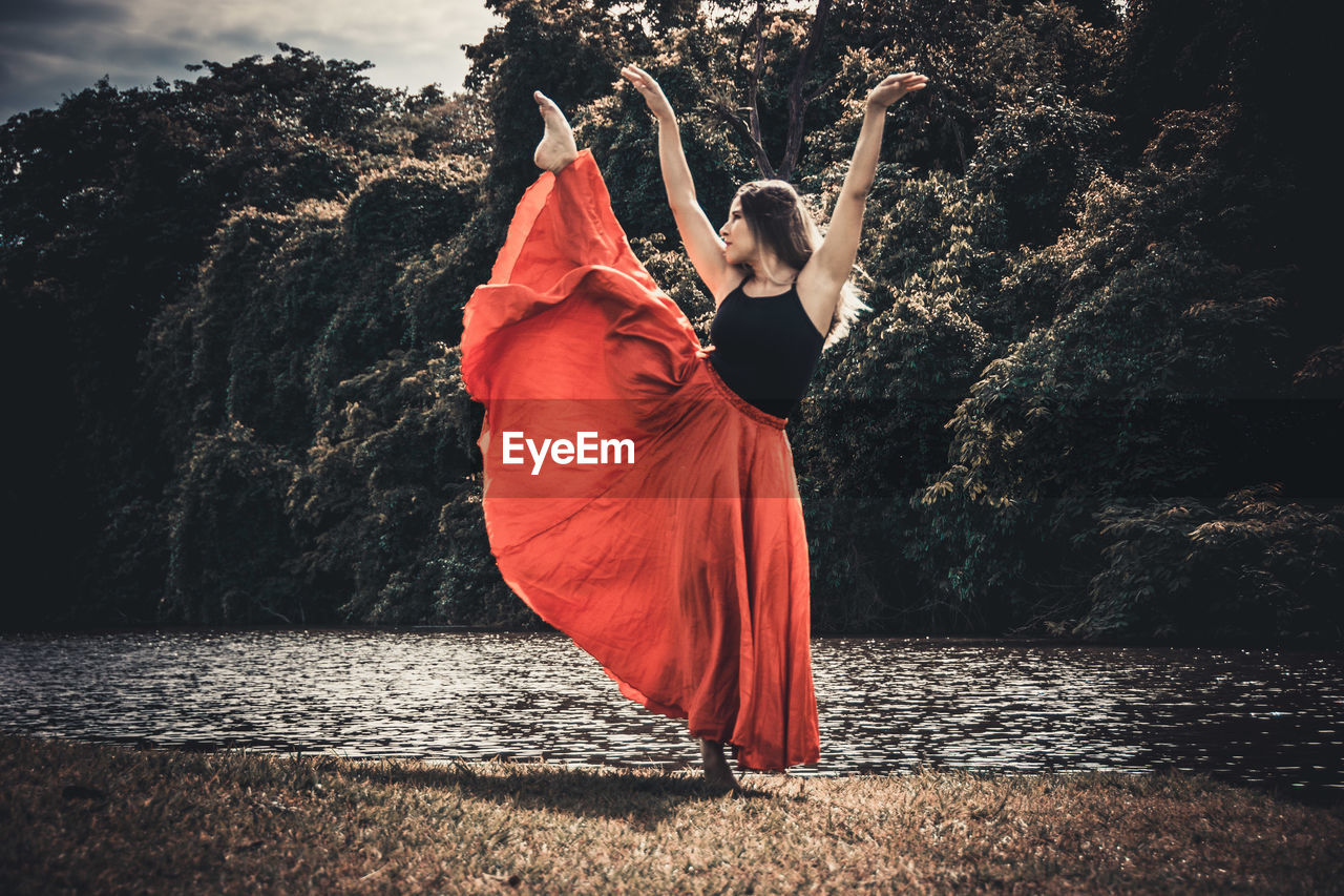 Young ballet dancer wearing red skirt while dancing in forest