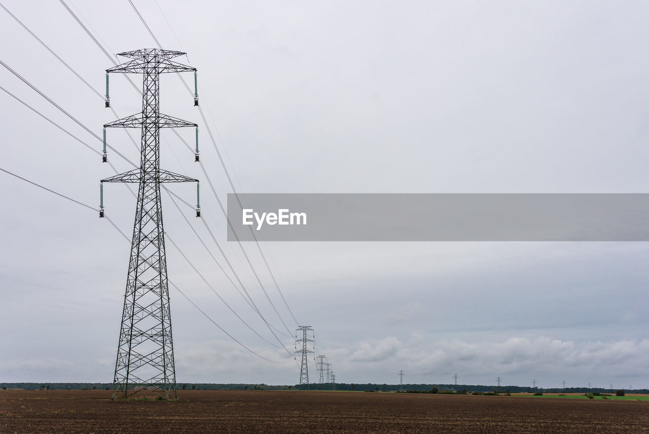 Extra high voltage overhead power line on large pylons, cloudy sky and copy space.