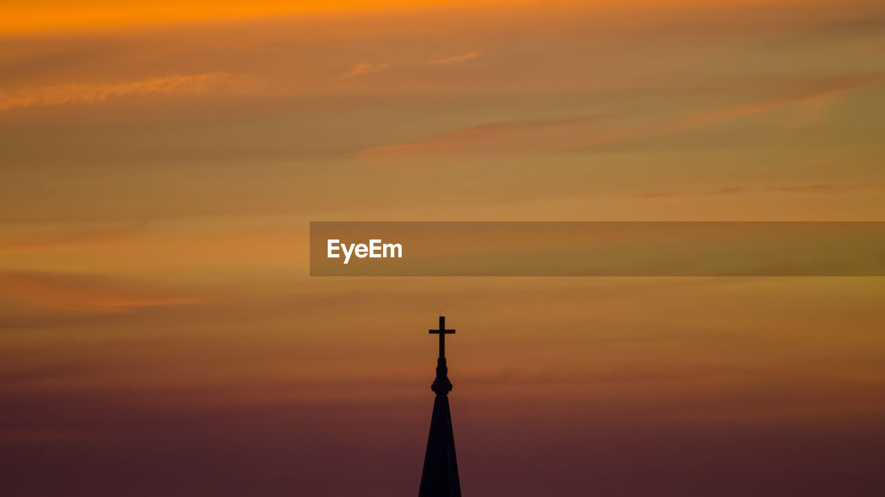 Cross on top of church against sky during sunset