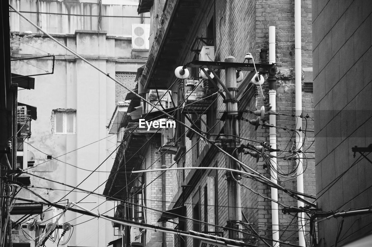 Low angle view of electric pole against buildings in city