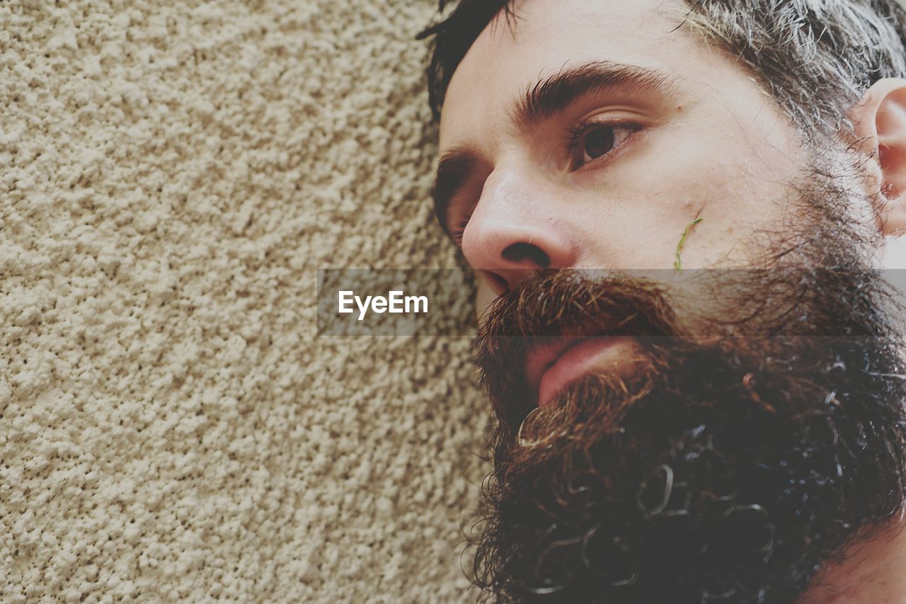 Close-up of bearded tensed man leaning on wall