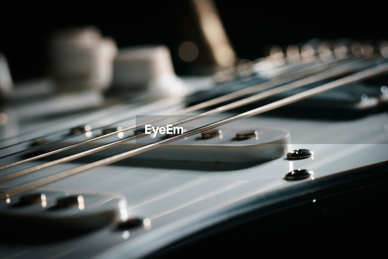 Close up picture of a black electric guitar on a black background.