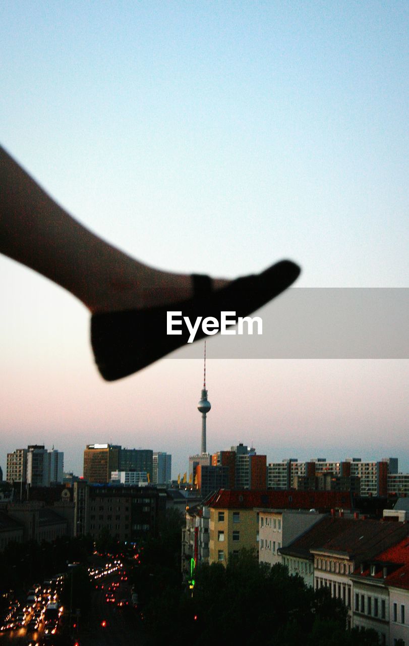 Optical illusion of cropped leg touching fernsehturm at sunset