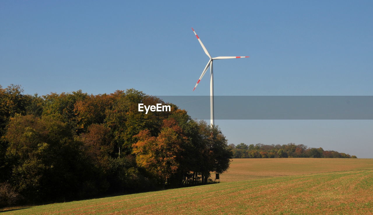 WINDMILLS ON FIELD AGAINST CLEAR SKY