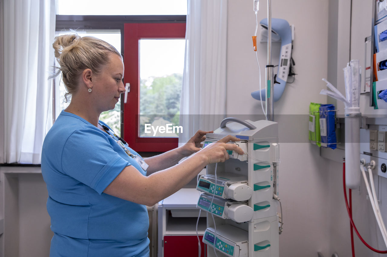 Female doctor examining medical equipment while standing in hospital