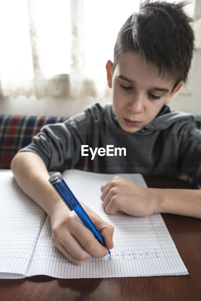 MIDSECTION OF BOY WITH TEXT ON PAPER