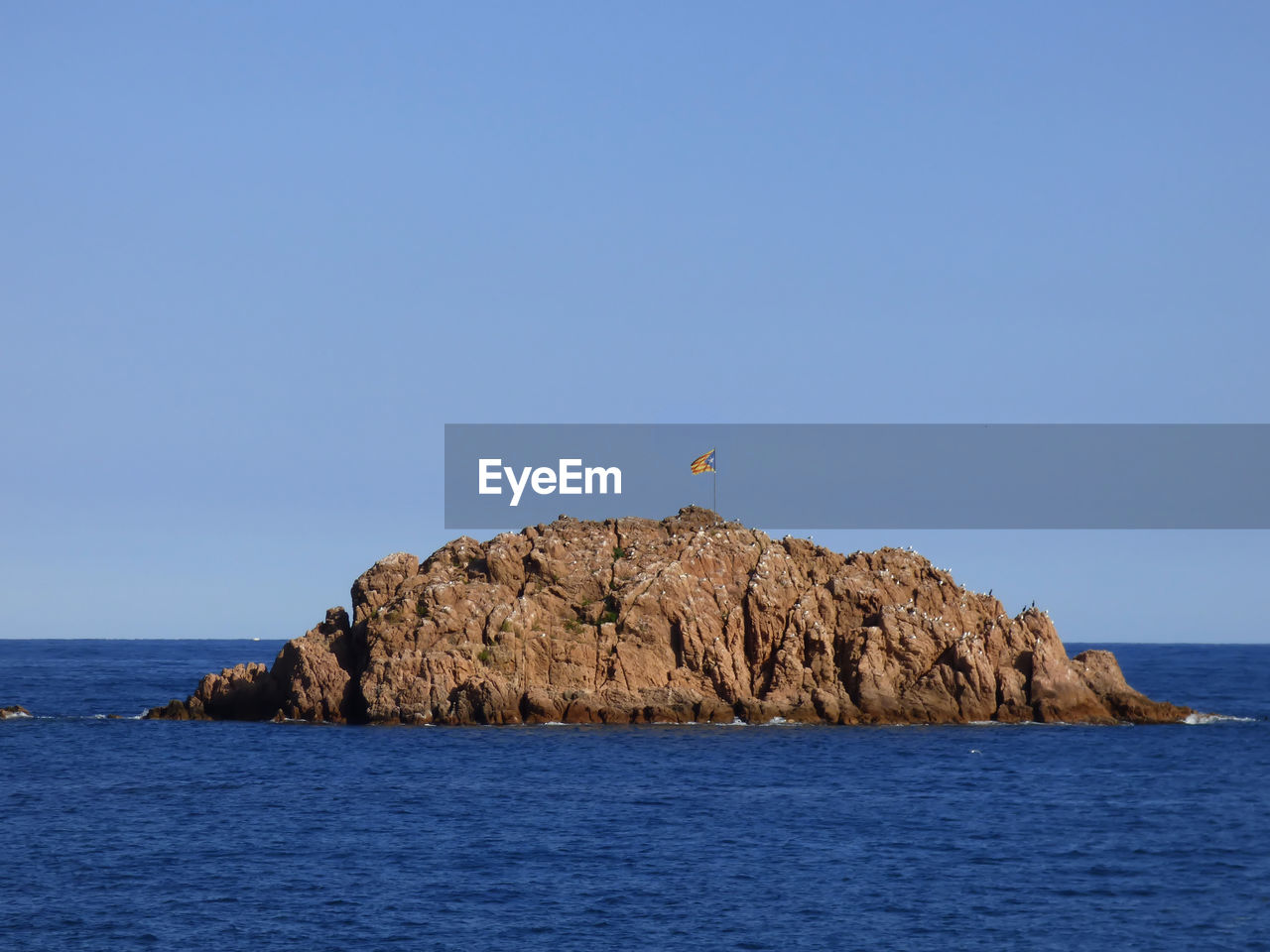 Rock formation in sea against clear sky