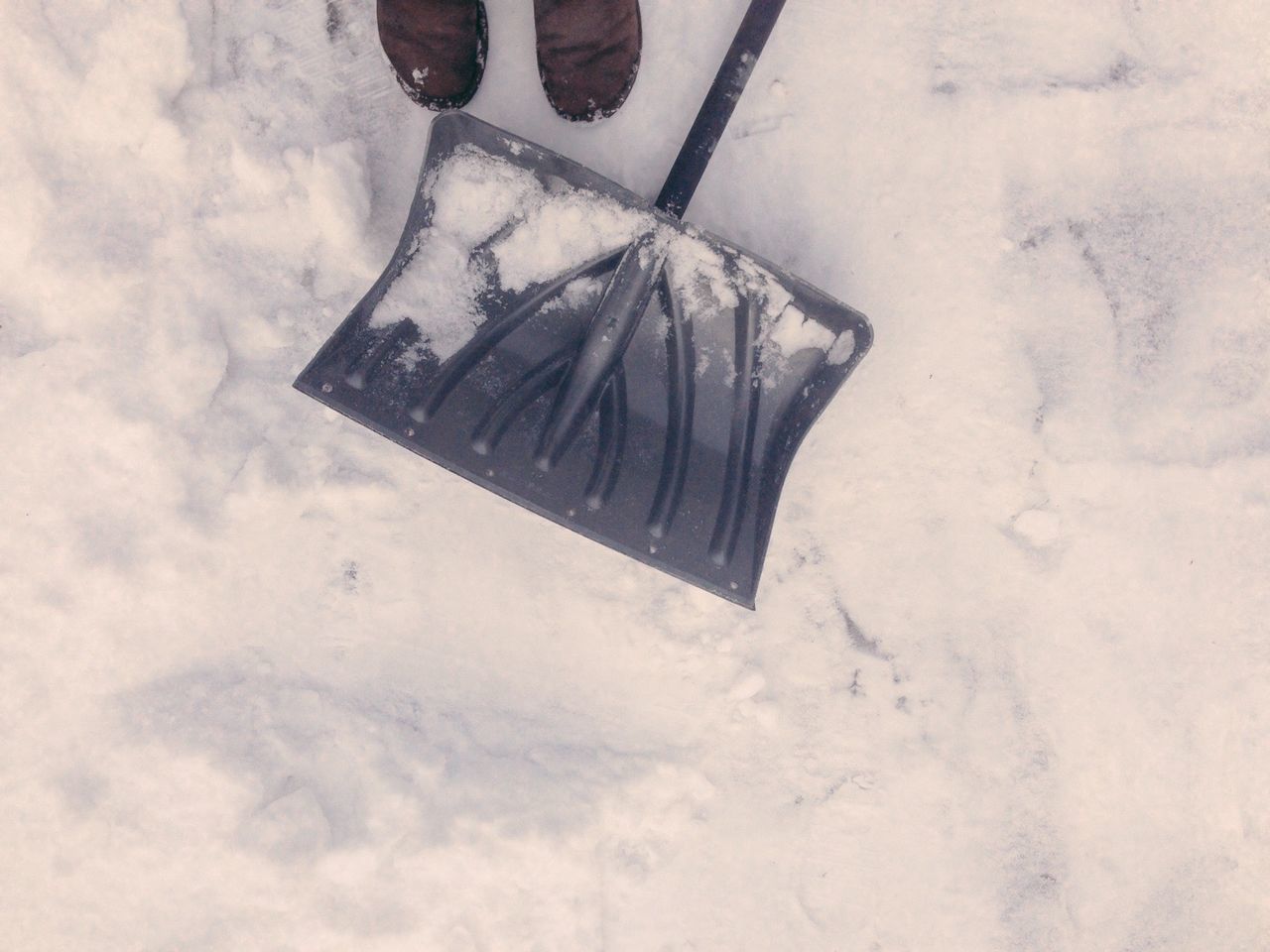 Man's feet with shovel in snow