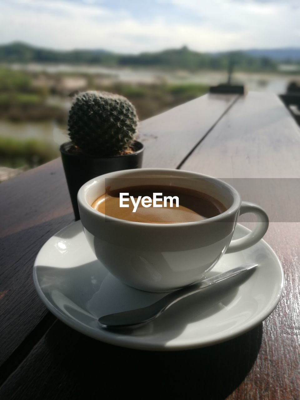 CLOSE-UP OF COFFEE CUP ON TABLE AGAINST BLURRED BACKGROUND