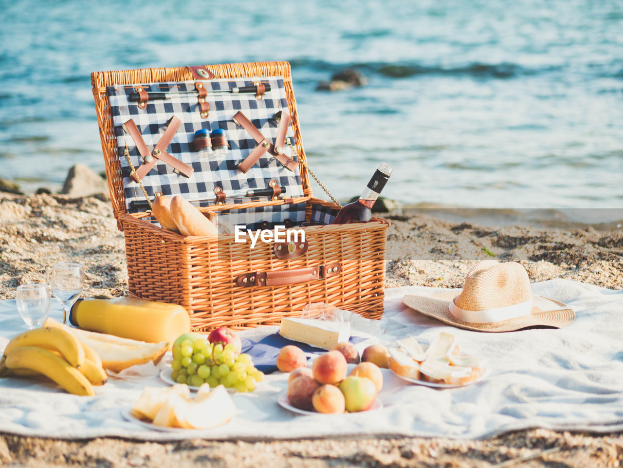 Various fruits in basket on picnic blanket at shore