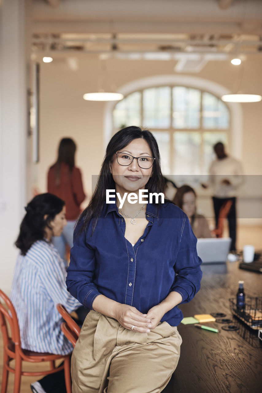 Portrait of smiling businesswoman sitting at desk in coworking office