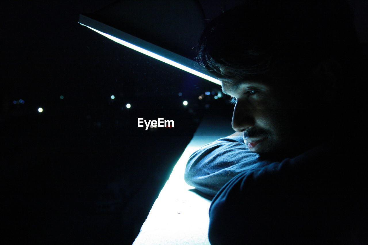 Portrait of young man looking away at night