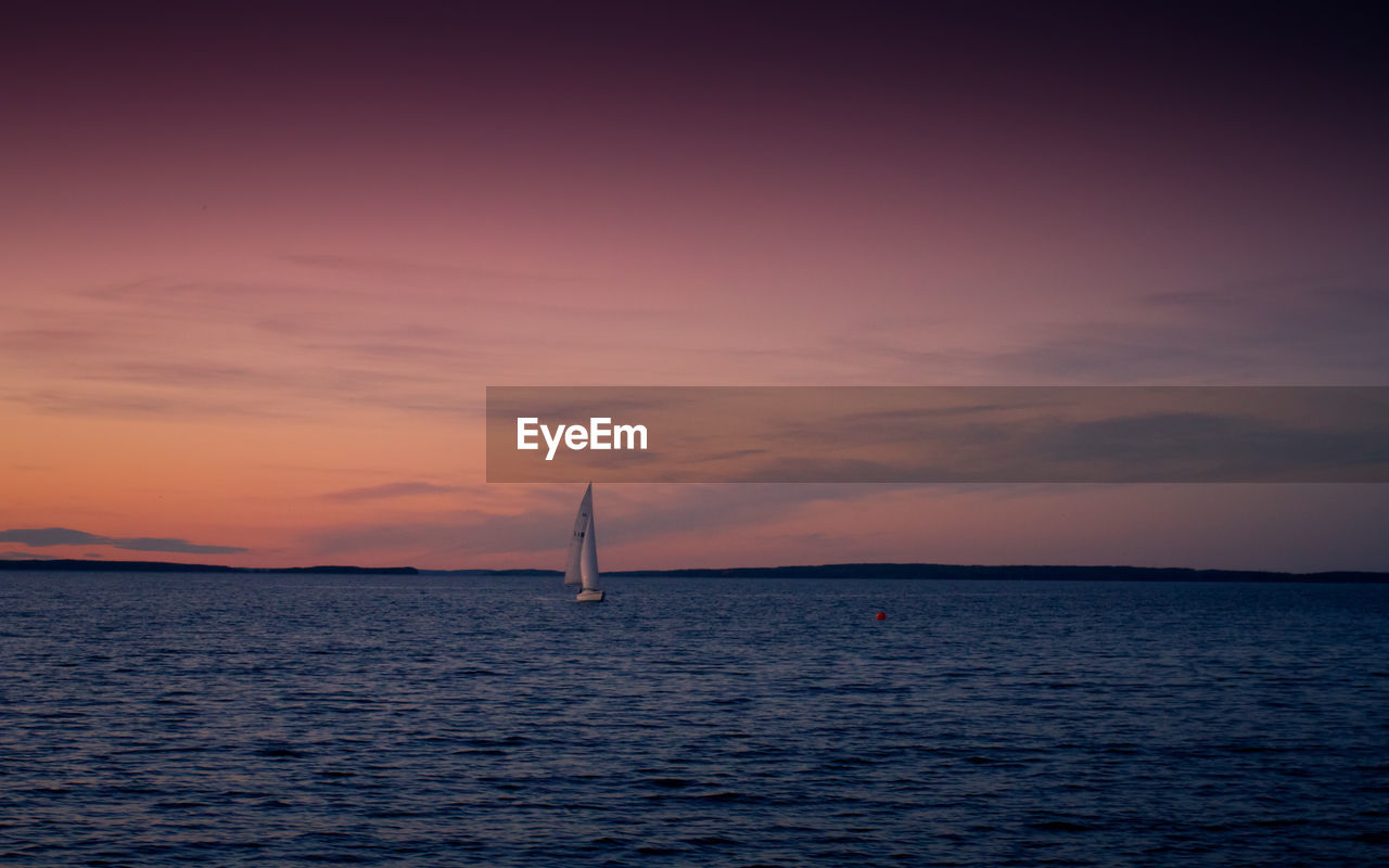 SAILBOAT SAILING IN SEA AGAINST SKY AT SUNSET