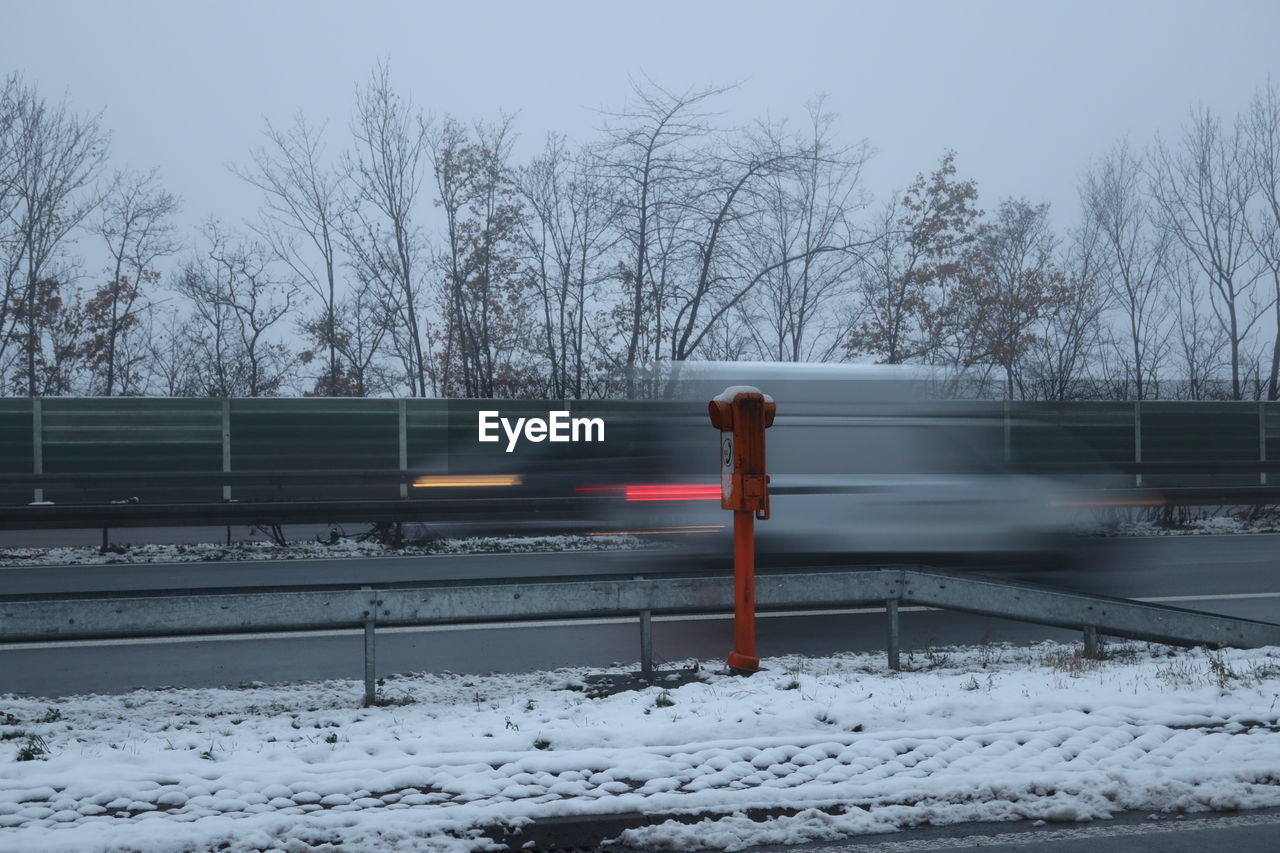 snow, winter, cold temperature, nature, bare tree, tree, transportation, rail transportation, sky, freezing, train, mode of transportation, transport, day, plant, track, railroad track, no people, outdoors, motion, railway, architecture, railing, frozen, public transportation, vehicle, road